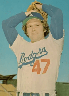 Andy Messersmith in mid-1970s Dodgers uniform—jersey number 47, arms raised in windup position, wearing a matching blue undershirt—captured during the era when he consulted with Dr. Mike Marshall on biomechanics and pitching reform.