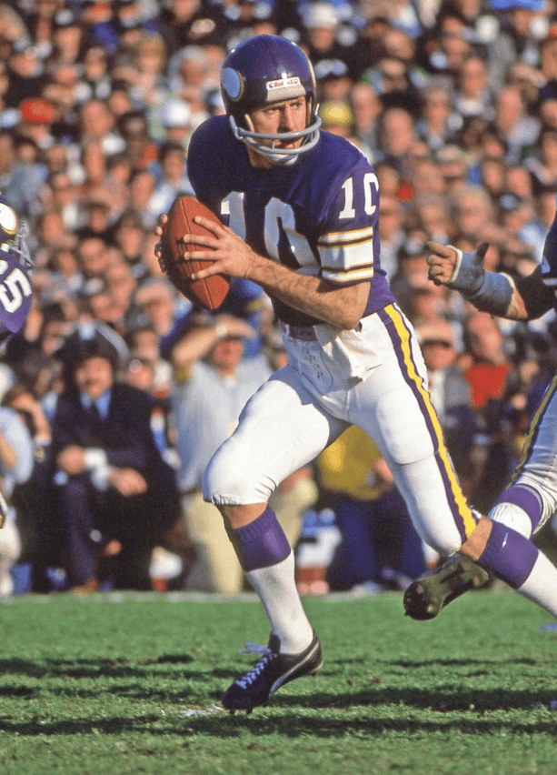 Fran Tarkenton in a 1970s Minnesota Vikings uniform—purple jersey with white numbers and gold trim—captured mid-play during the era when he consulted with Dr. Mike Marshall on biomechanics and pitching reform principles.