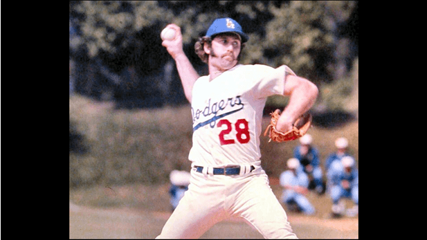 Dr. Mike Marshall mid-pitch in 1974 Dodgers home uniform, demonstrating pronation mechanics with thumb up and palm facing third base—illustrating his injury-preventive delivery.