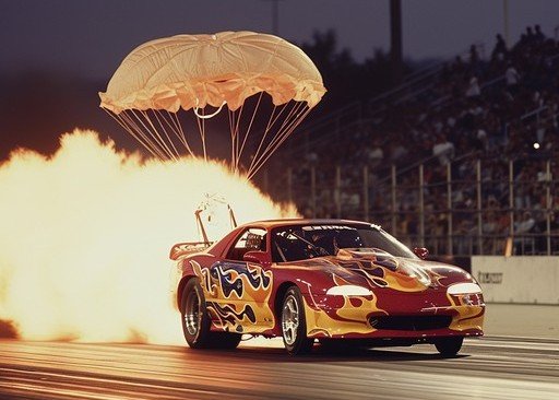 Drag race car with parachute brakes deployed at full speed — visual analogy for Dr. Mike Marshall's cerebellum deceleration principle in wrist weight training